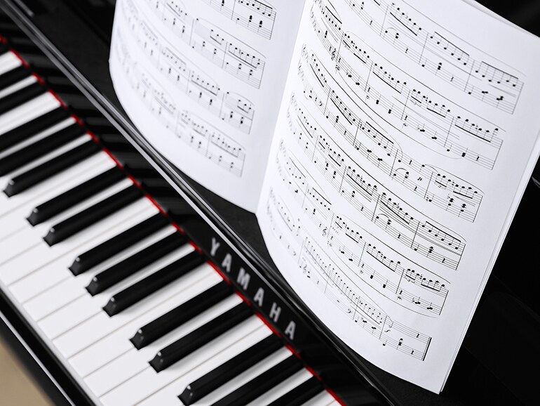 ياماها كلافينوفا CLP-885PE مع نوتة موسيقية على الحامل