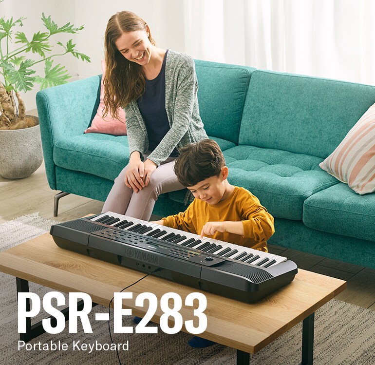أب وطفل يعزفان بسعادة على آلة PSR-E283 الموضوعة على الطاولة