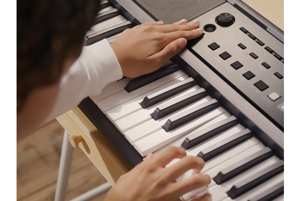 الفتاة تجرّب طرقًا مختلفة للعزف على آلة PSR-E383.
