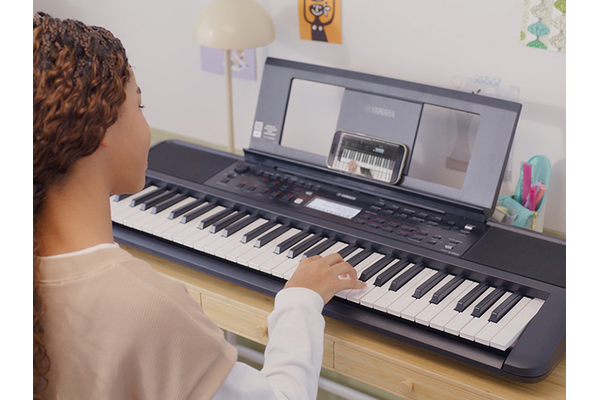 الفتاة تعزف على آلة PSR-E383 برضا واهتمام.