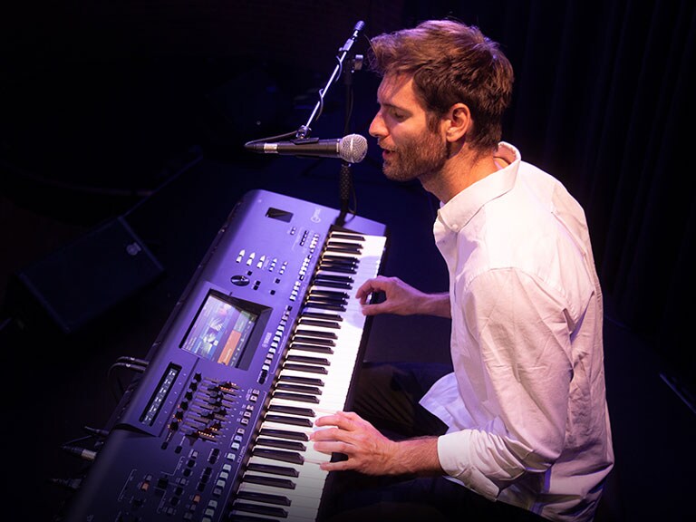 رجل يغنّي في الميكروفون أثناء العزف على آلة جينوس 2