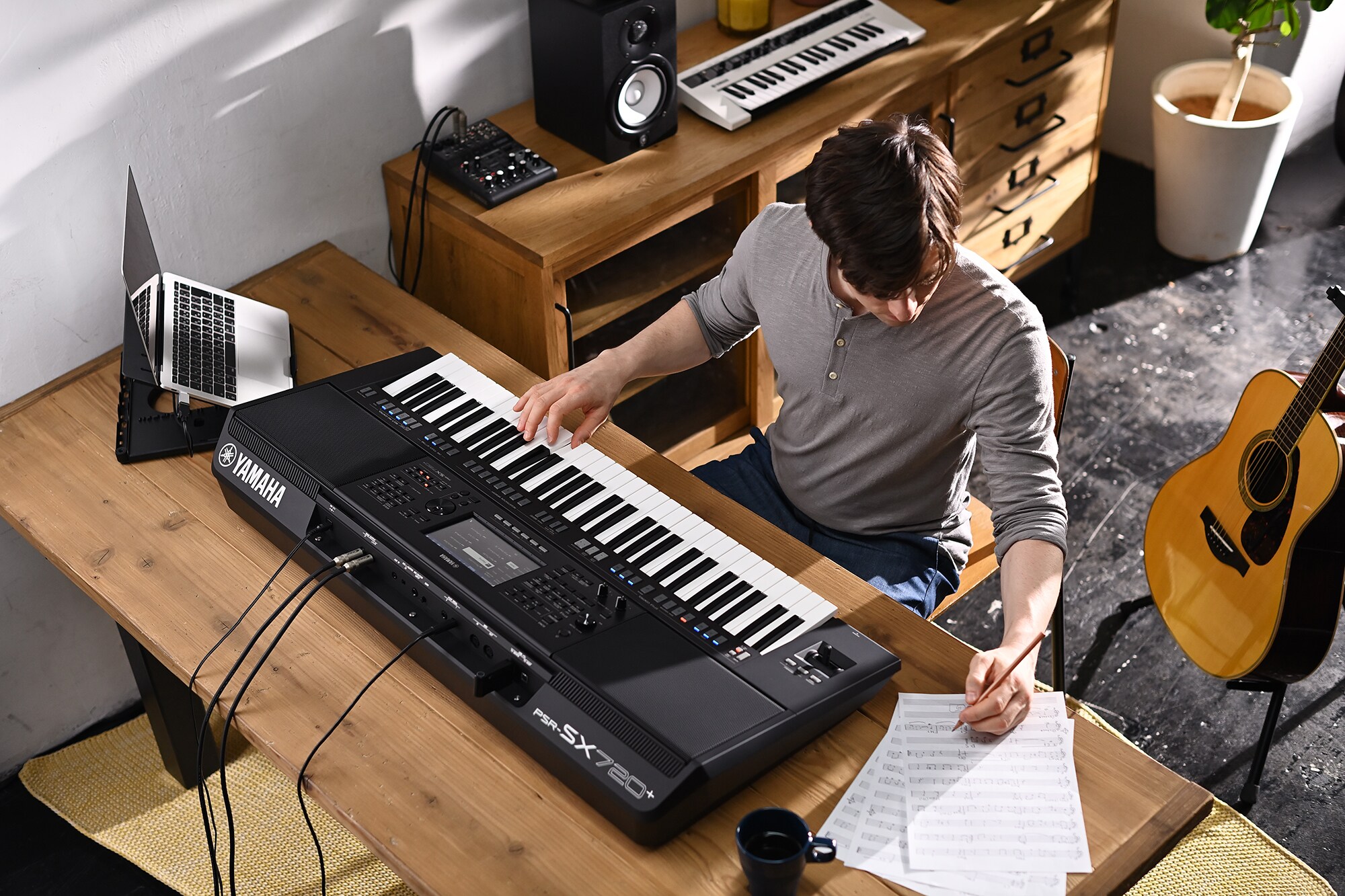 Photo of a person writing on sheet music while playing the Yamaha Arranger Workstation PSR-SX720+